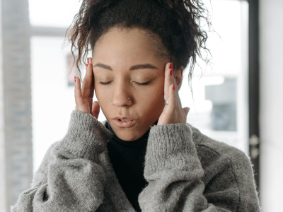 Woman holding her head with worry, showing common health concerns.